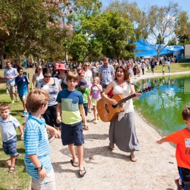 HaMo'Robyn Solovei playing guitar and leading children on an outdoor park walk
